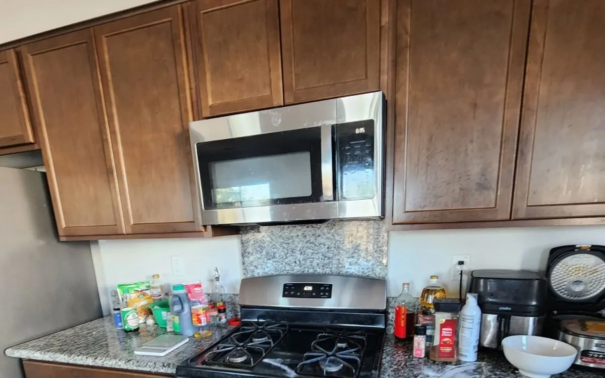 Wood kitchen cabinets above a gas range and microwave