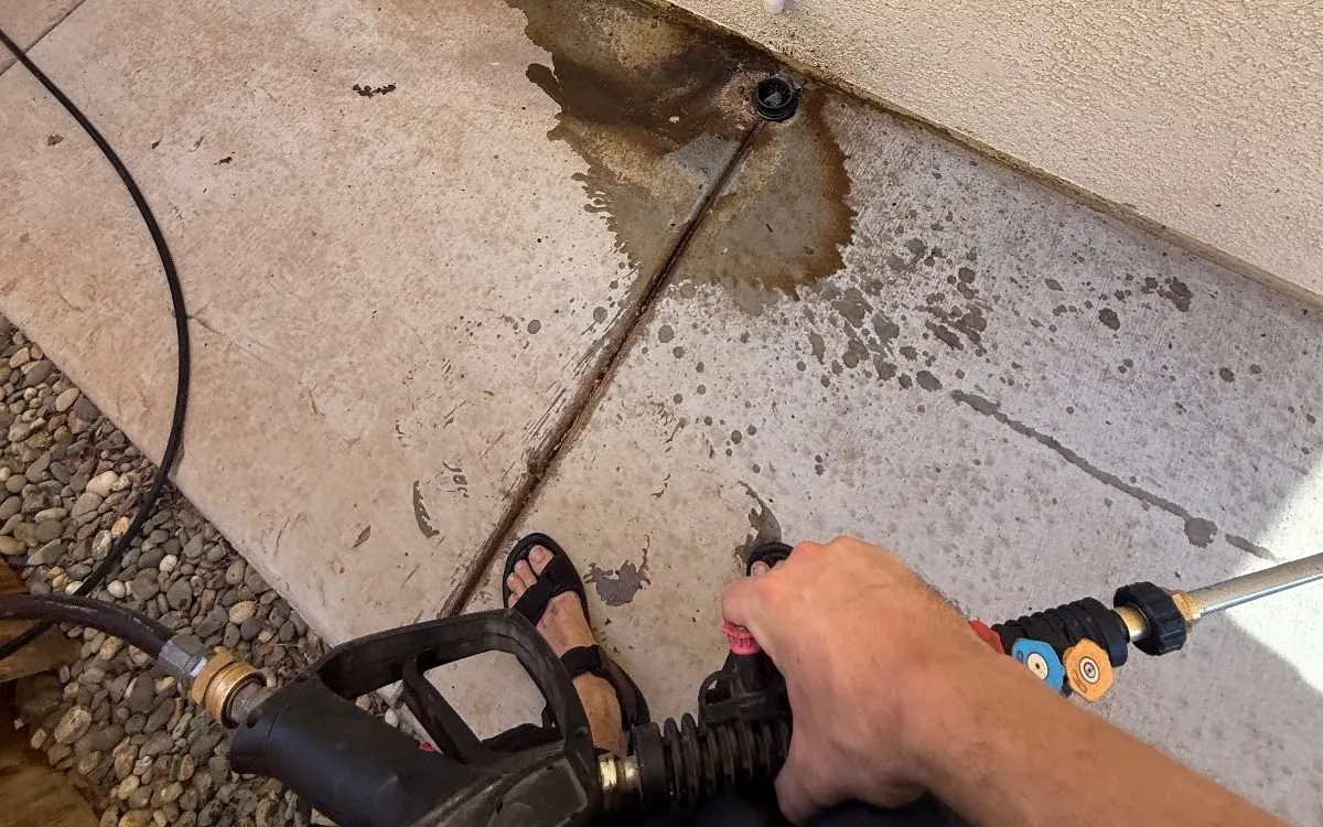 Pressure washer wand over a stained concrete side yard