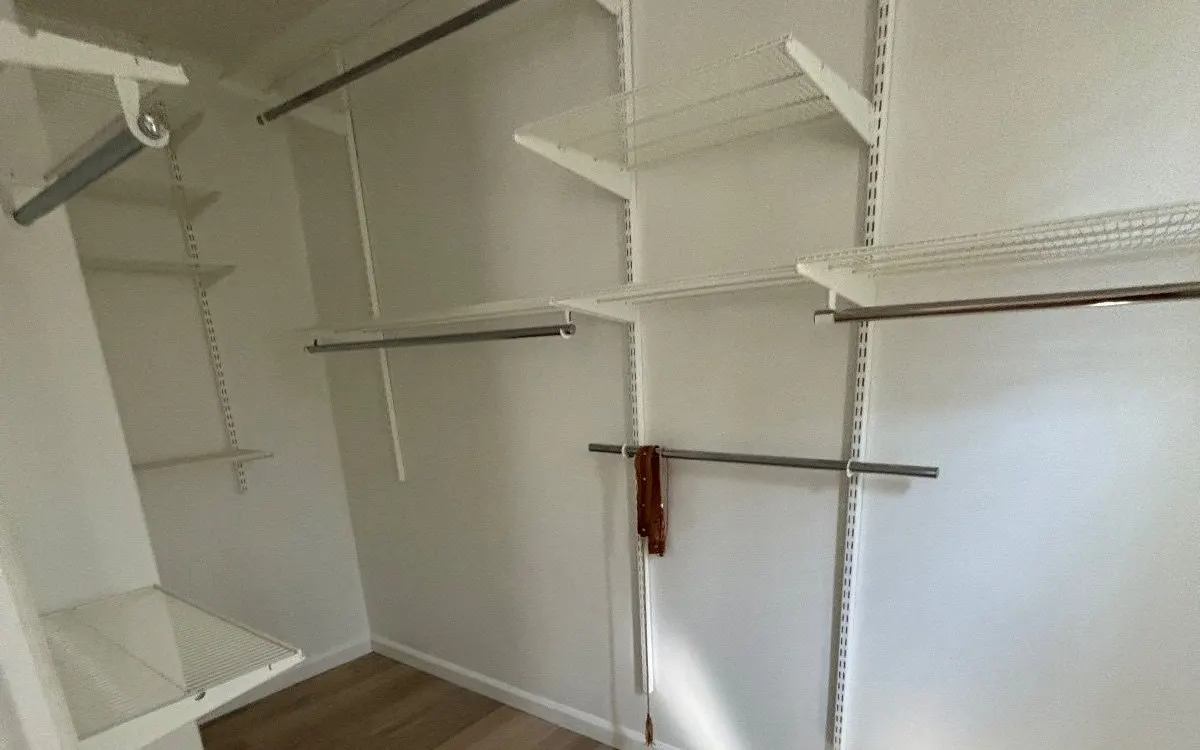 Empty walk-in closet with wall-mounted shelves and hanging rods