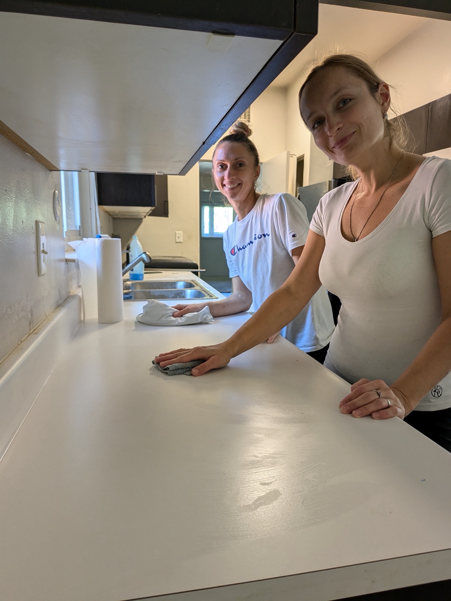 Two cleaners wiping down a kitchen counter together